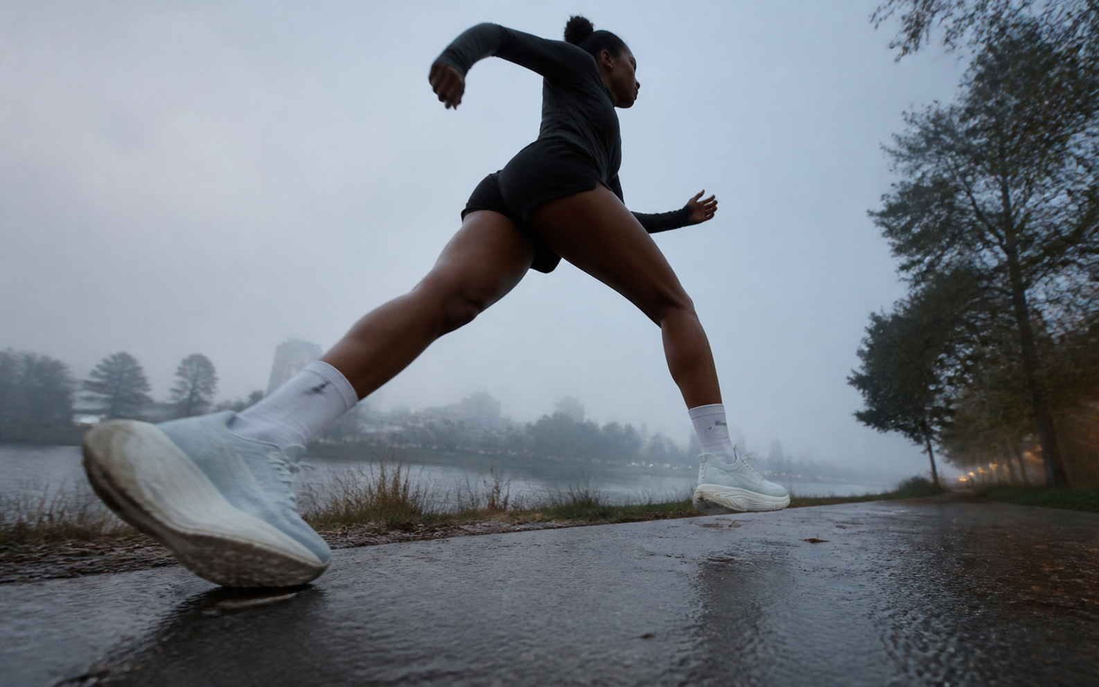 Runner moving beside a misty riverside path
